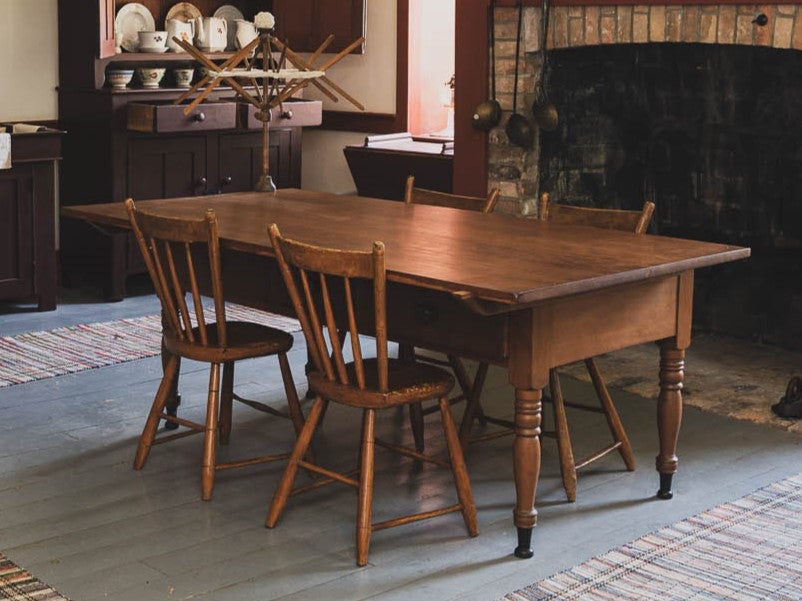 A wooden kitchen table, four wooden chairs placed around it.