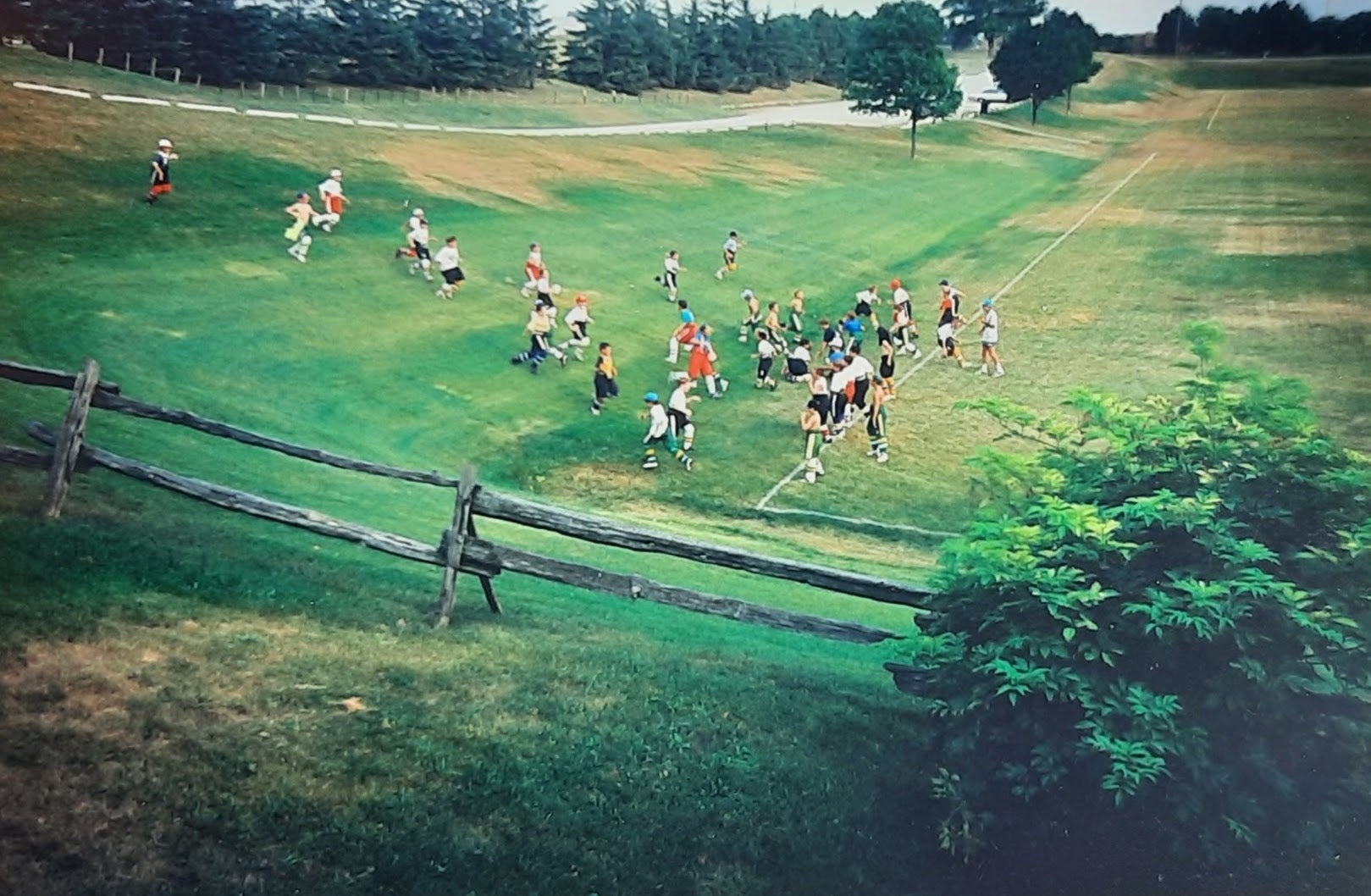 A group of kids in sports uniform run up and down the hill