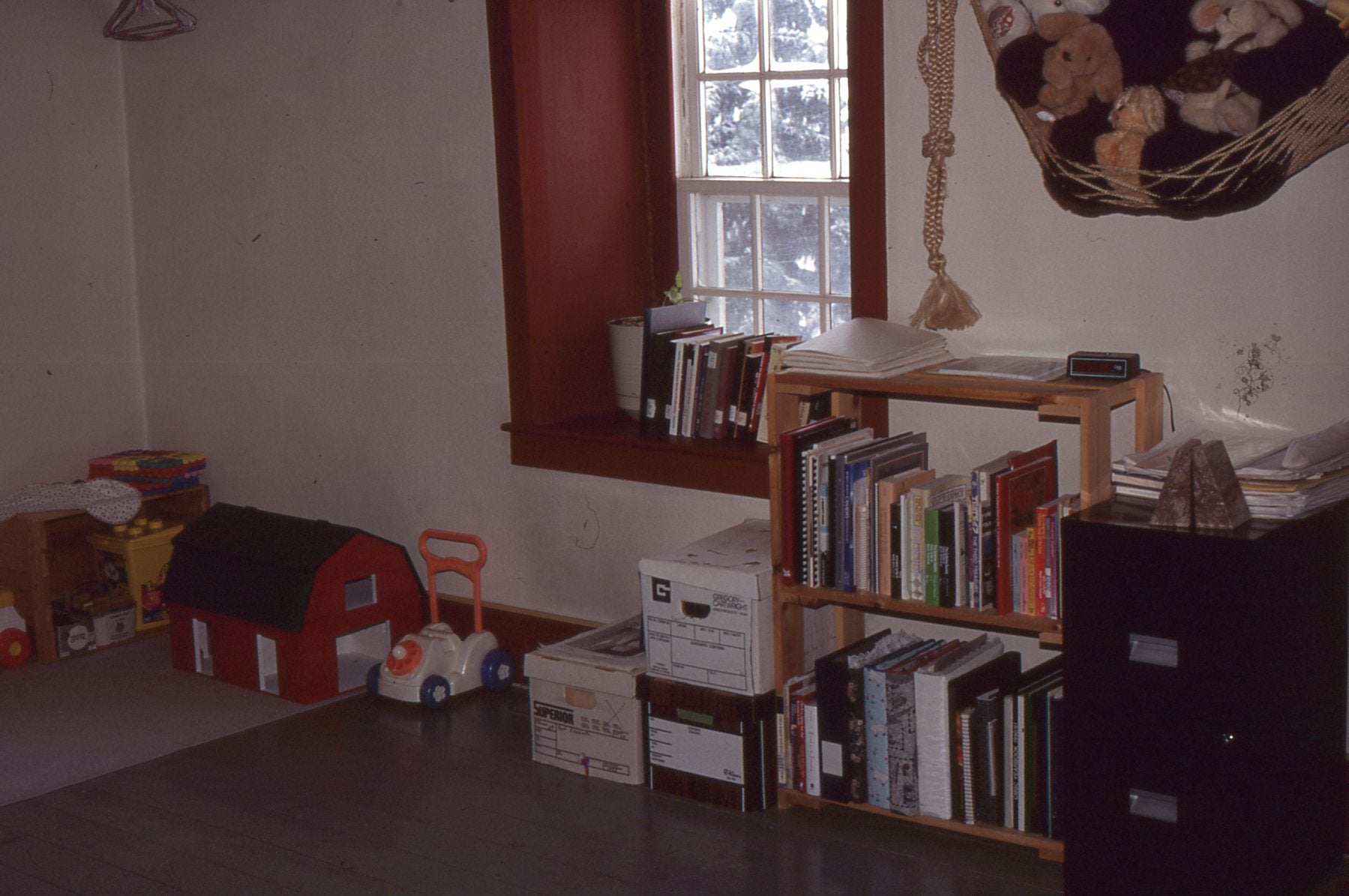 The opposite wall of Arlyn and Judith's bedroom, with books shelves, children's toys and a window