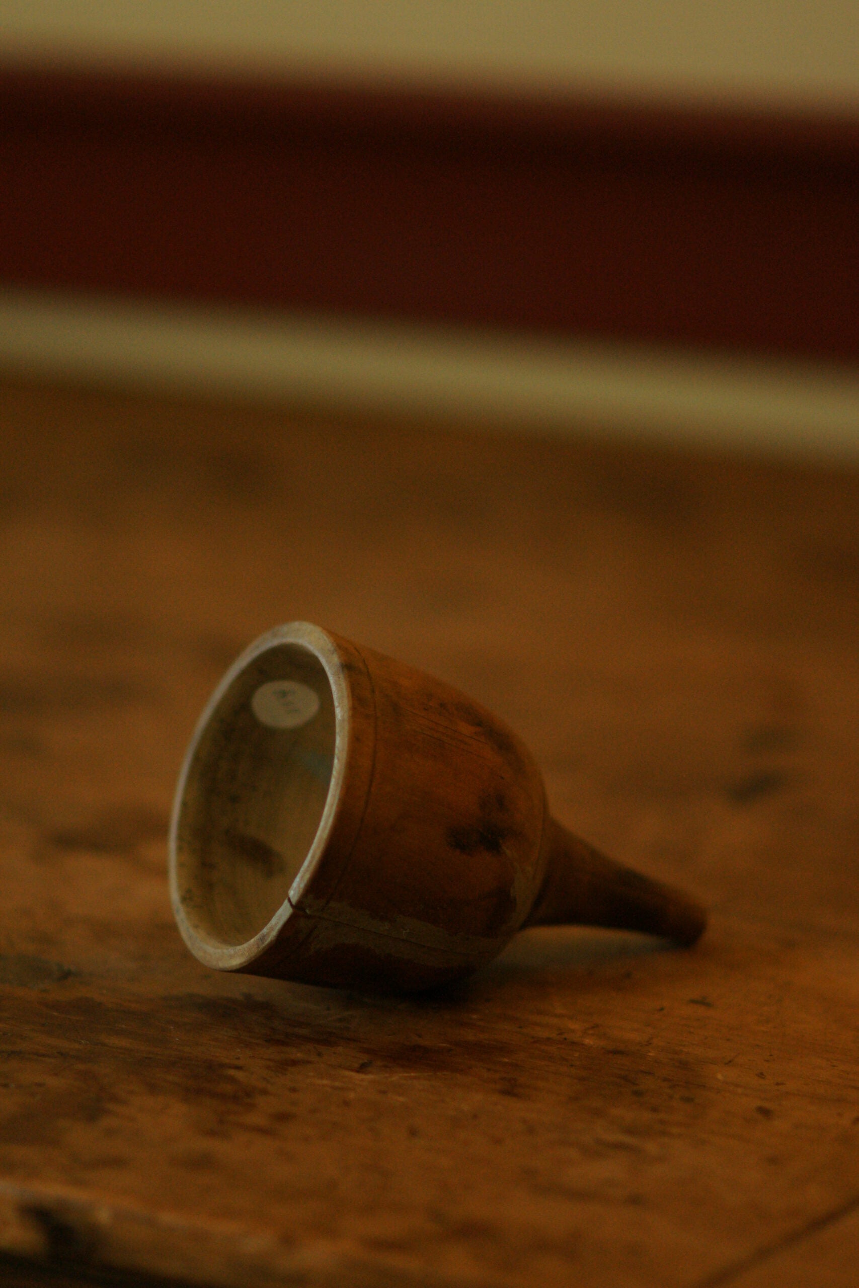 A wooden funnel, shaped like a bell, sits on it's side on a wooden counter
