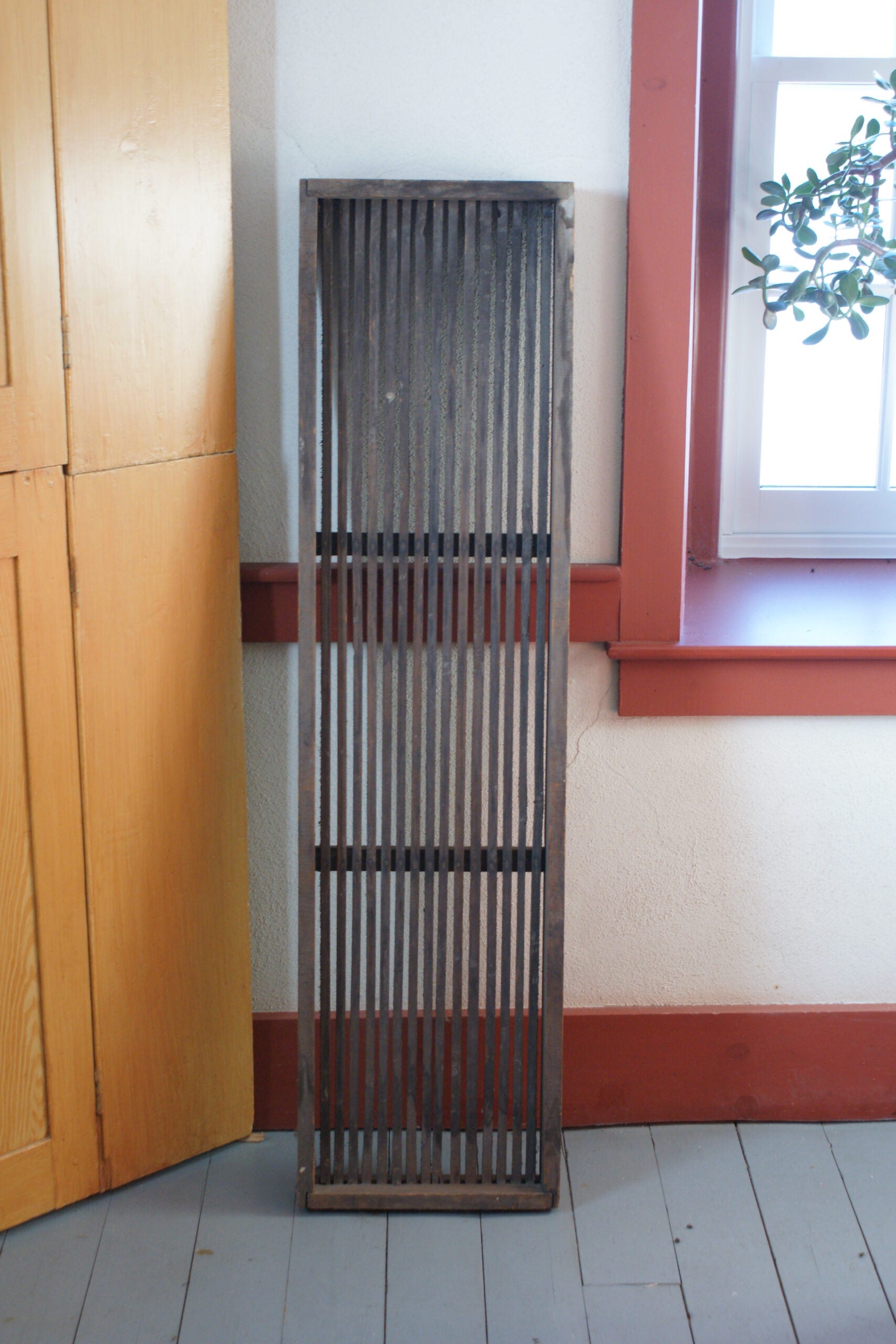 A tall, slatted brown wood rack, which would be placed over a sink to let wet dishes dry over.