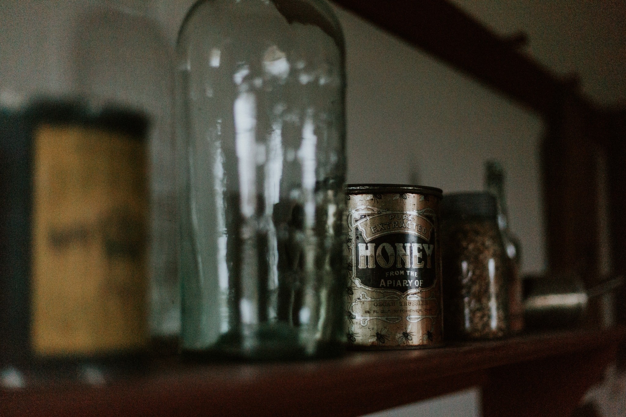 A shelf holds a tall glass bottle, and an old silver tin.