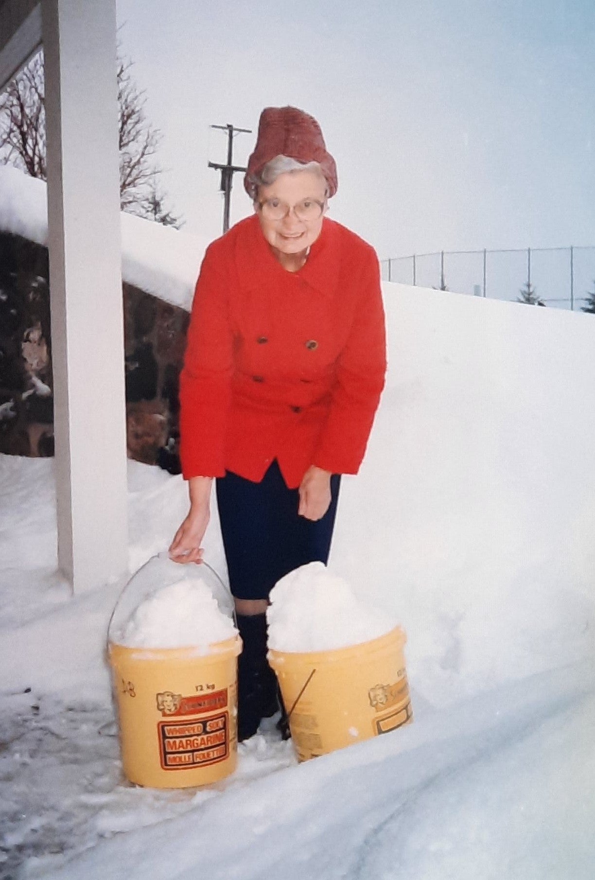DOrothy wears a red jacket, carrying yellow buckets of snow