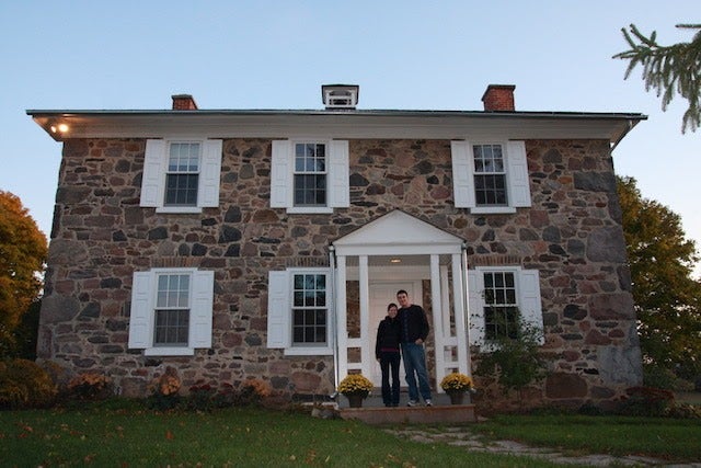 Two Brubacher House hosts stand outside of Brubacher House on a summer evening