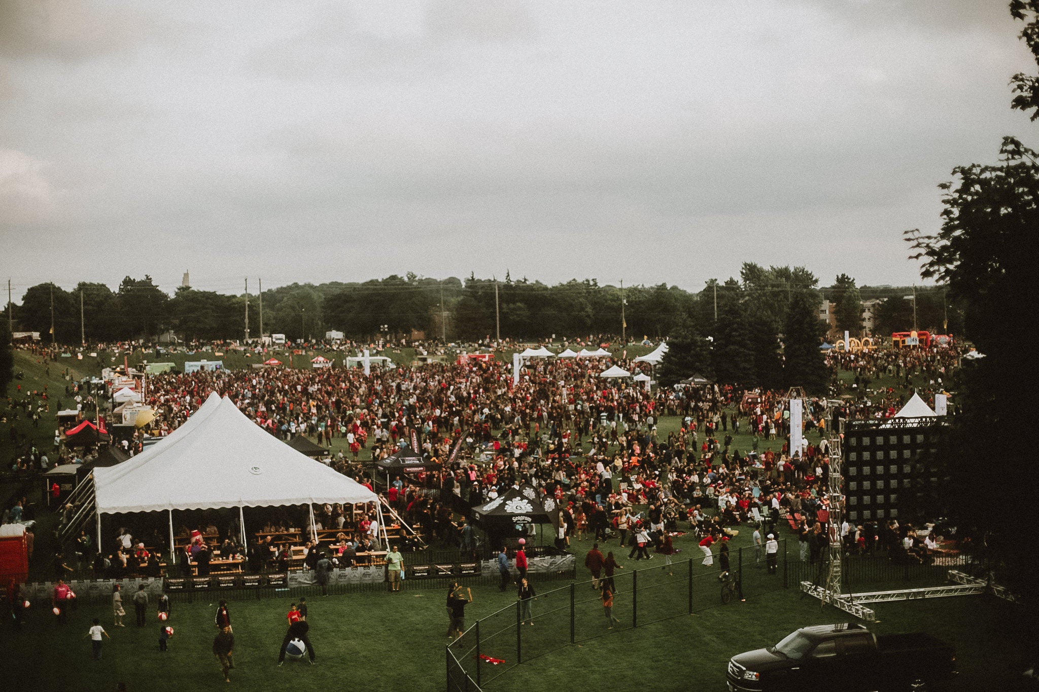 A large crowd gathers at Colombia Lake fields during Canada day. A large white tent its nearby.