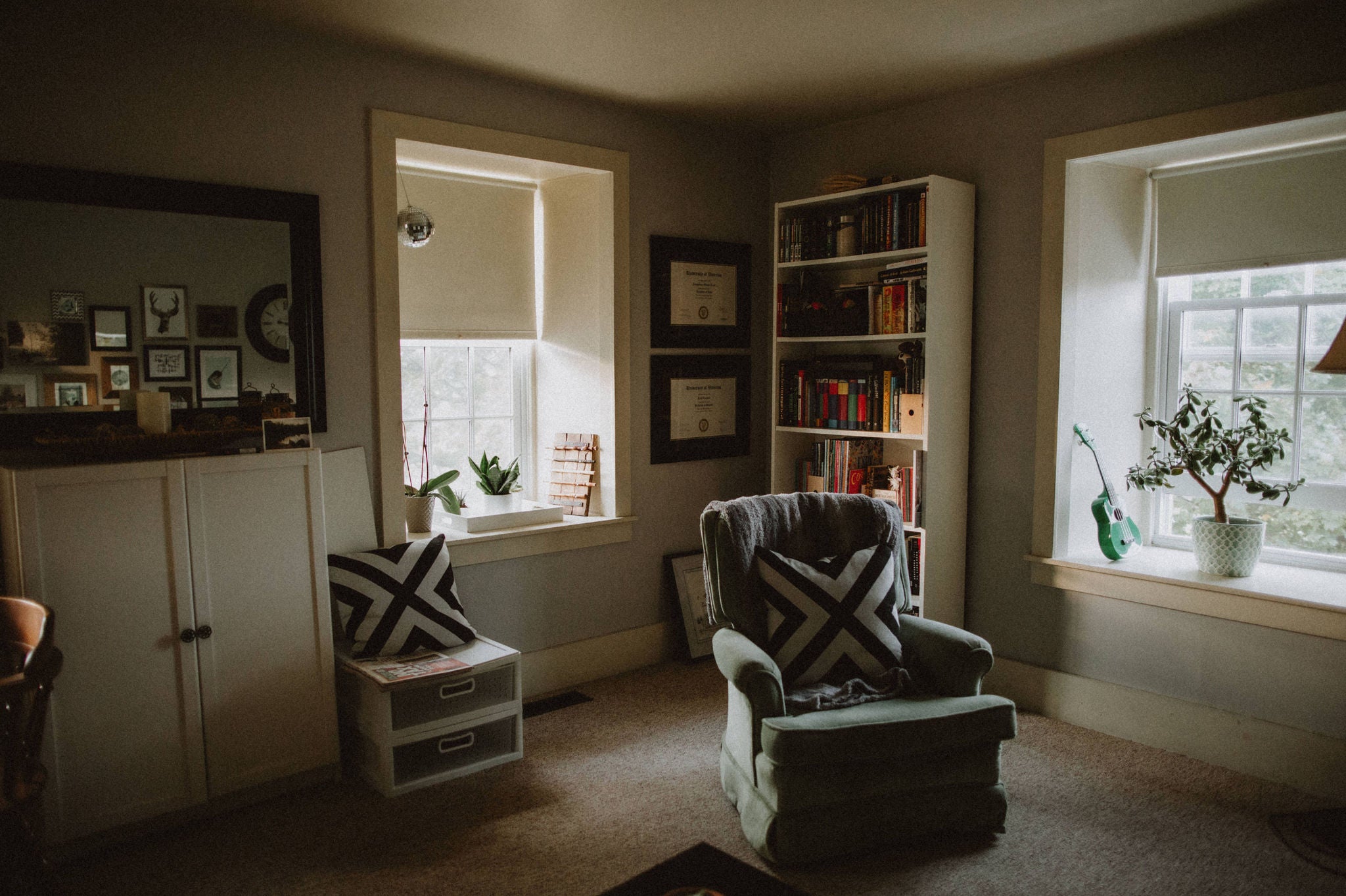 A corner of the brubacher house living room, with two reclining chairs and a book case.