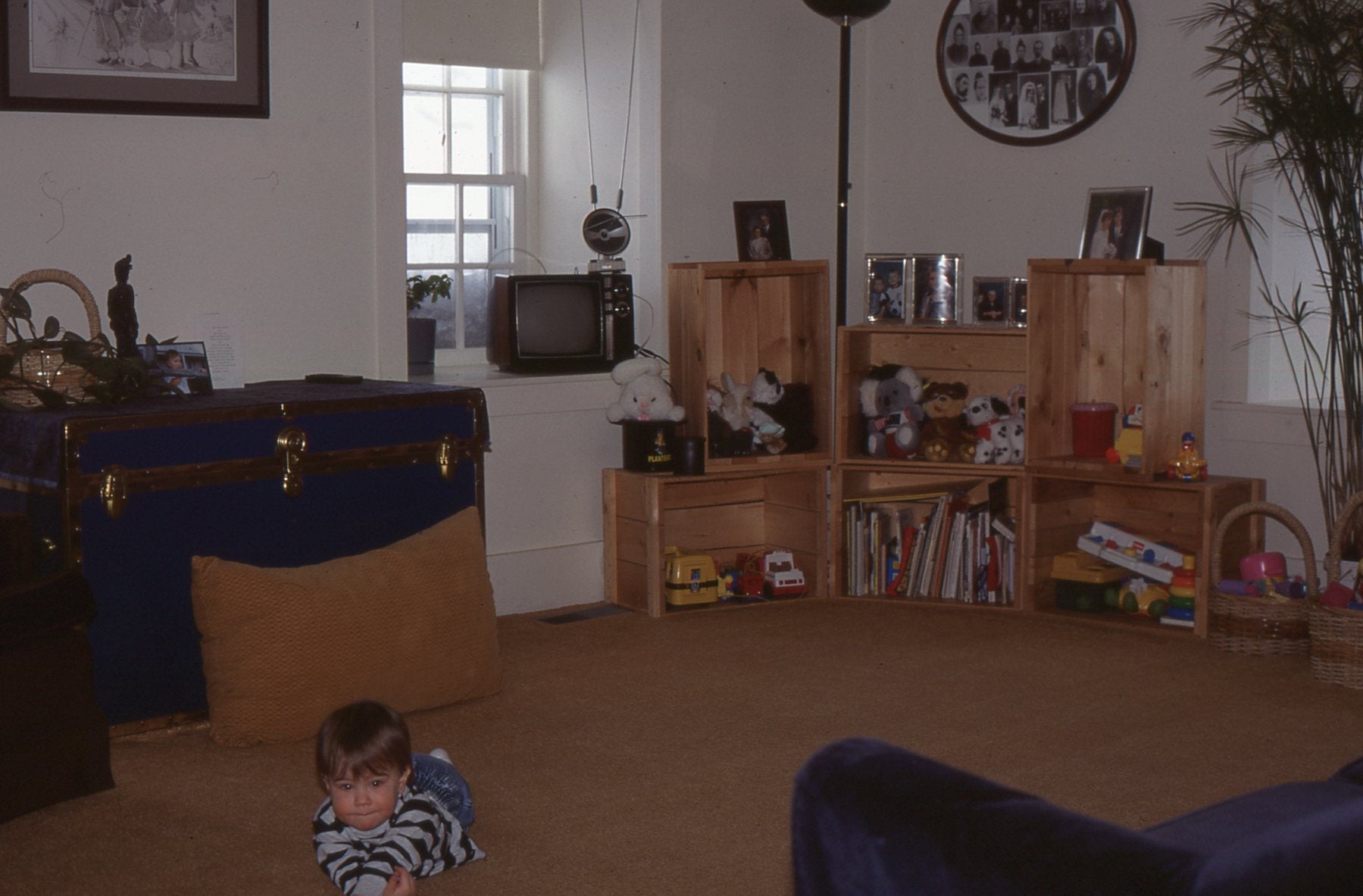 a dull photo of the brubacher house living room. In the bottom left, a small child lays on the floor, smiling at the camera.