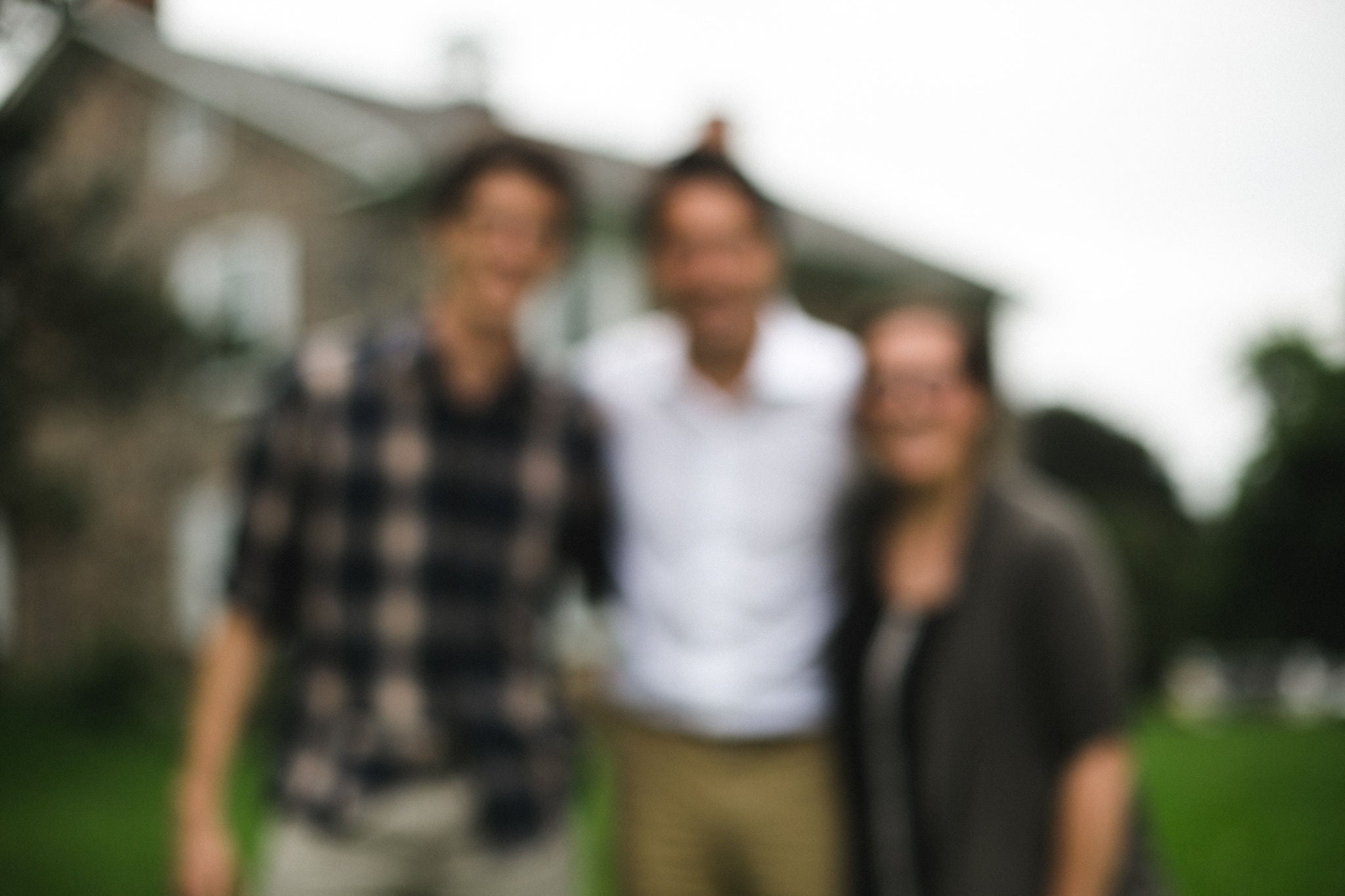 A blurry photo, with justin trudeau in the middle, Jacquie and Karl on either side of him, burbacher house (blurrily) in the background.