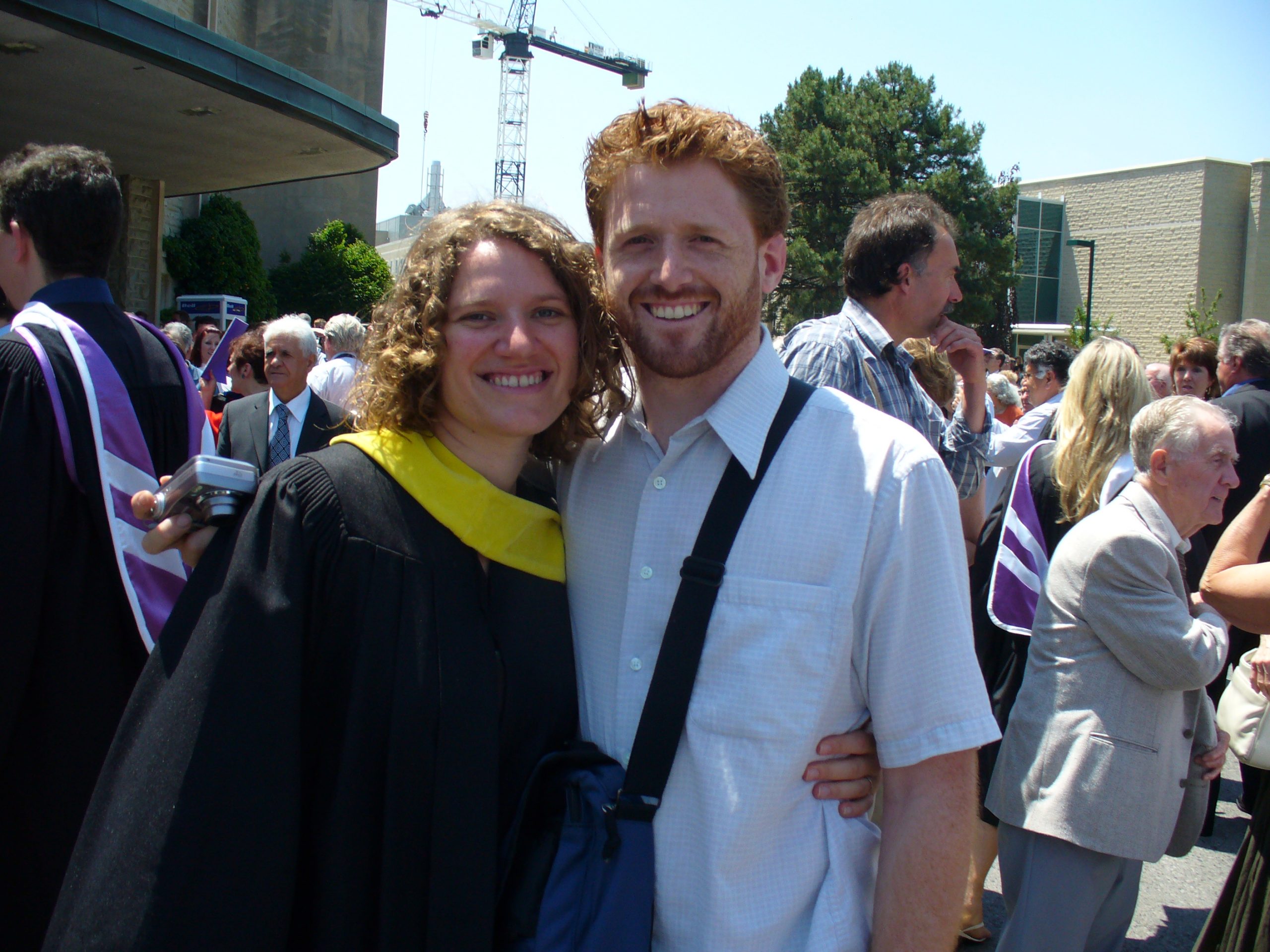 Bethany, in graduate robes, takes a photo with Brandon at convocation cermeonies
