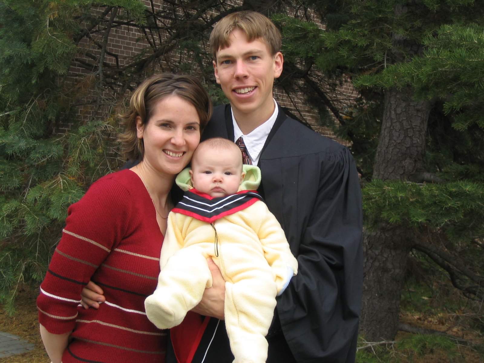 Colin and Jennie take a photo with their young child during graduation