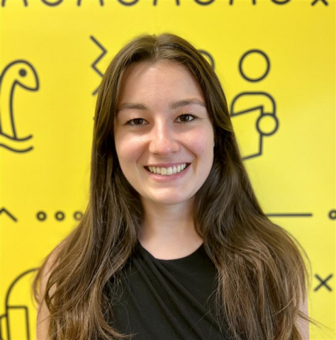 Person in a black t-shirt standing in front of a yellow banner with black branded UWaterloo logos.