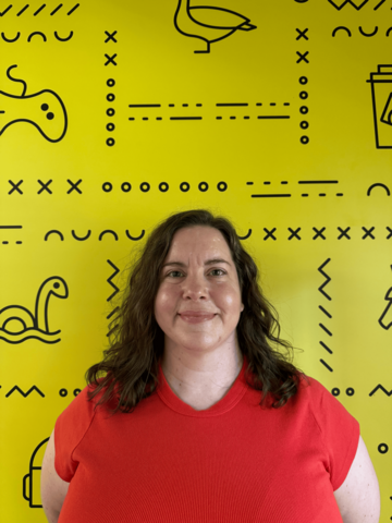 Person in a bright red t-shirt, standing in front of yellow banner with black UWaterloo logos.