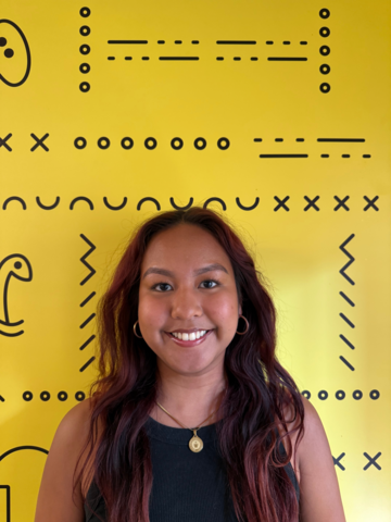 Person in a black tank top, standing in front of yellow banner with black branded UWaterloo logos.