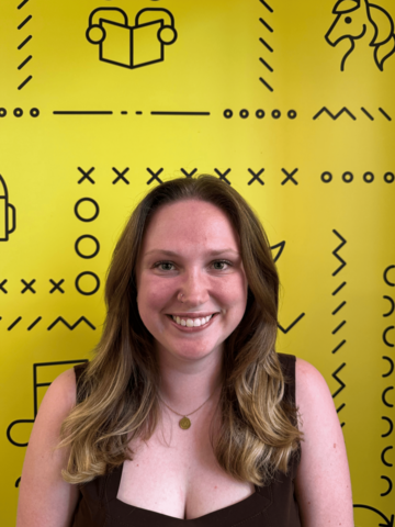 Person in a black tank top standing in front of a yellow banner with black branded UWaterloo logos. 
