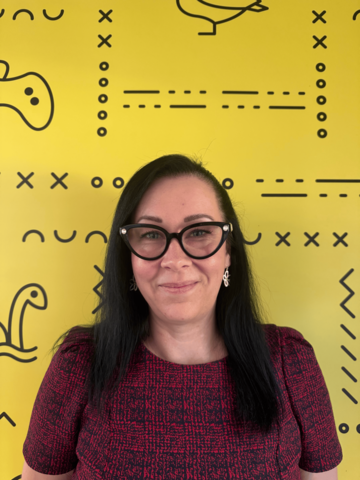 Person in a burgundy t-shirt, standing in front of yellow banner with black branded UWaterloo logos.