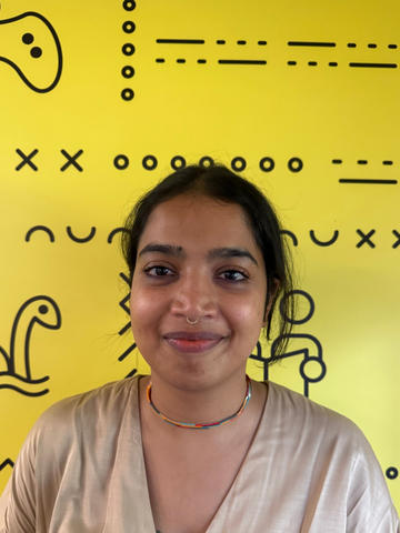 Person standing in a beige t-shirt in front of a yellow banner with black UWaterloo logos. 