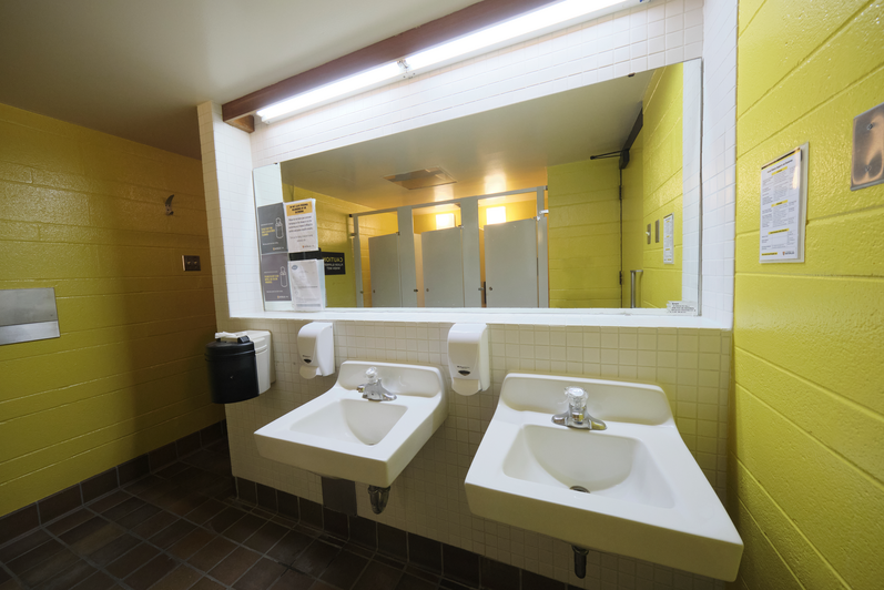 Minota Hagey Washroom showing 2 sinks, and a mirror reflecting toilet stalls. 