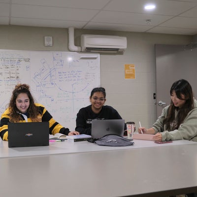 Three students studying together in a communal study room at Claudette Millar Hall.