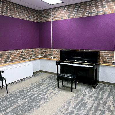 Village 1 piano room, with one grand piano, chairs around the room and purple walls.