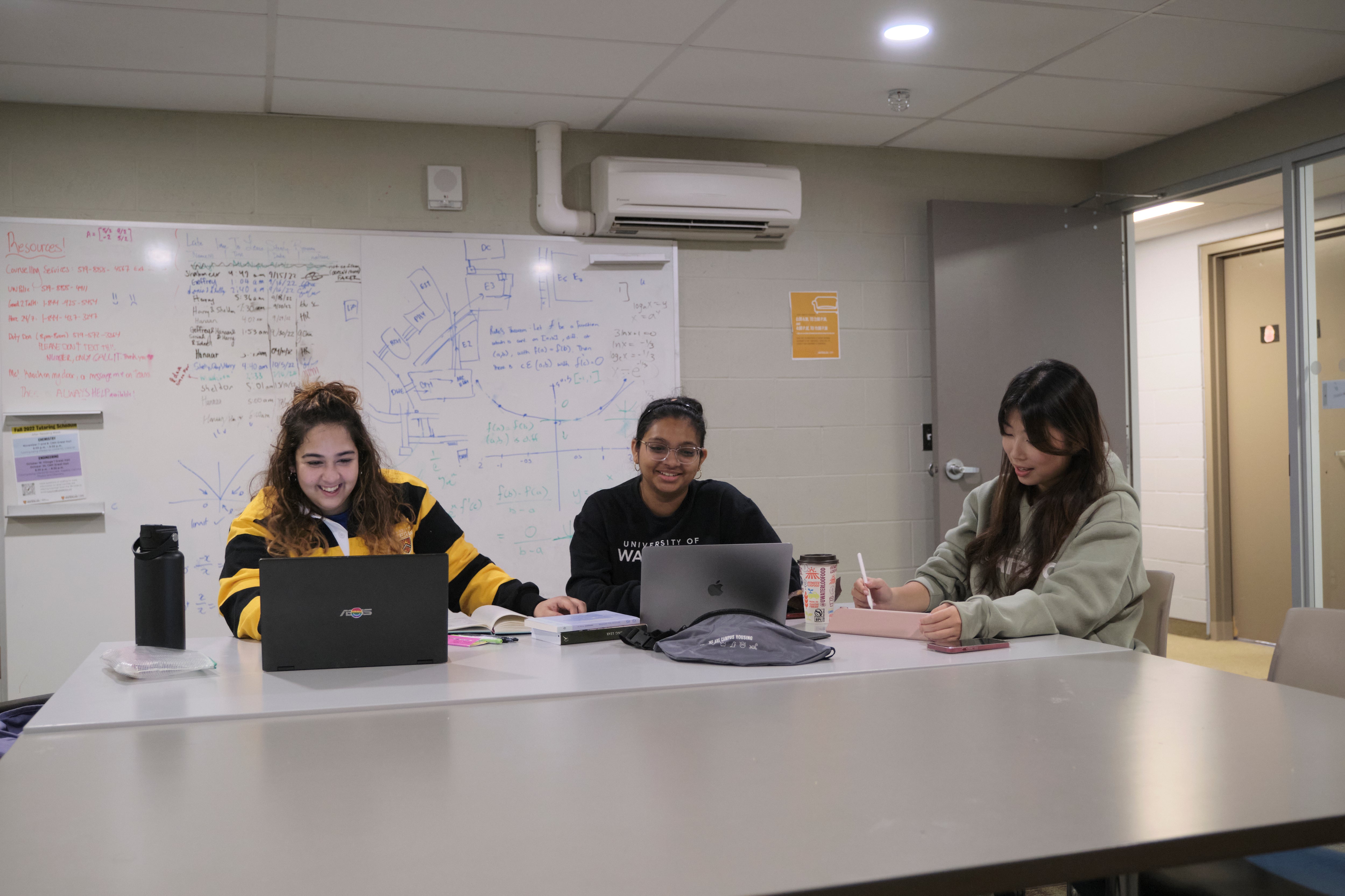 Three students studying together in a communal study room at Claudette Millar Hall.