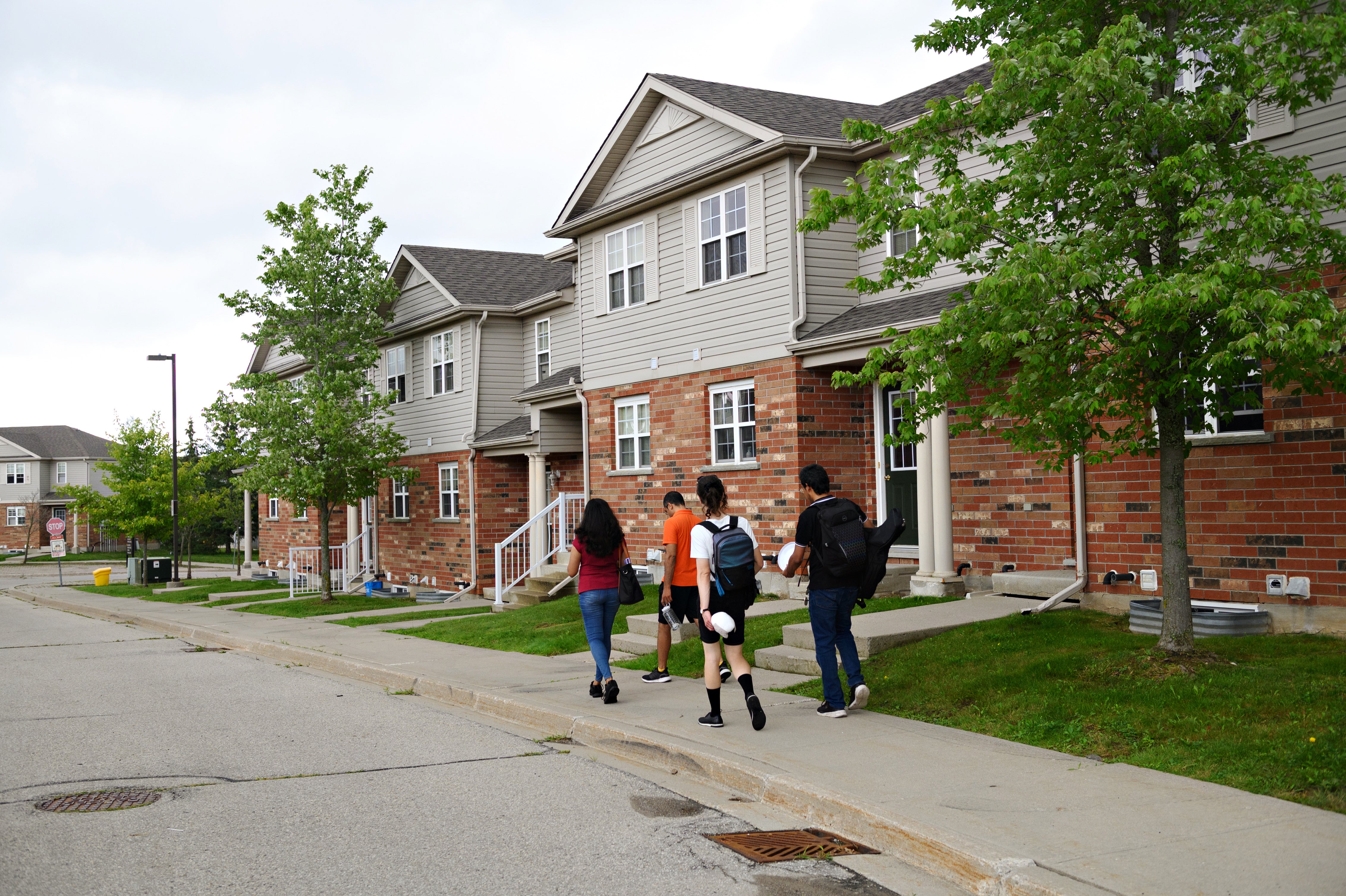 4 students walking with their backs turned past the CLV townhouses