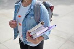 person walking with books in arms