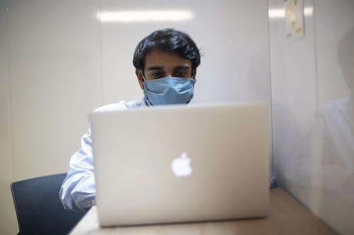 Person using a computer wearing a face mask