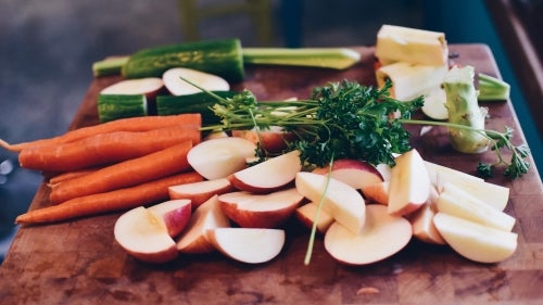 Apples, carrots, cucumber, and parsley on a cutting board
