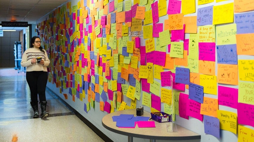 Student looks at a board full of sticky notes