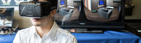 student stands in front of monitors with protosight virtual reality unit on his face