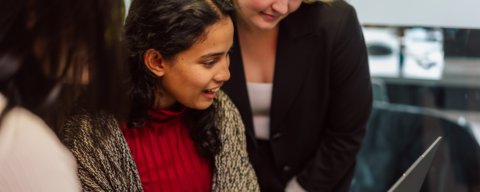 Student looking at laptop with two people beside her