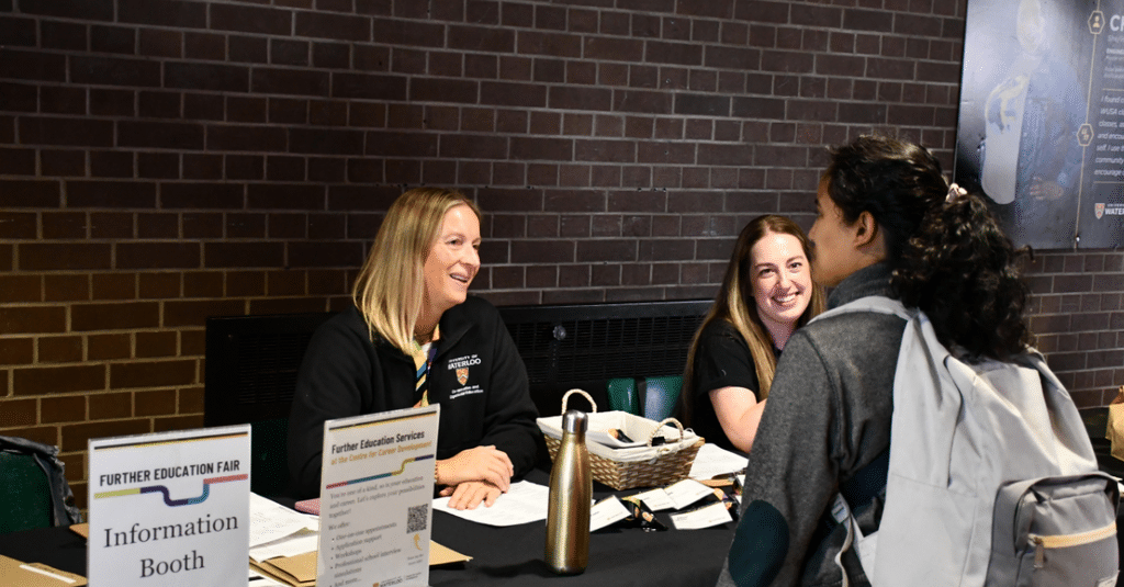 two women talking to a student wearing a backpack
