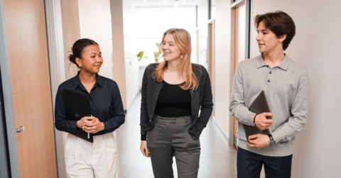 three people talking in a hallway