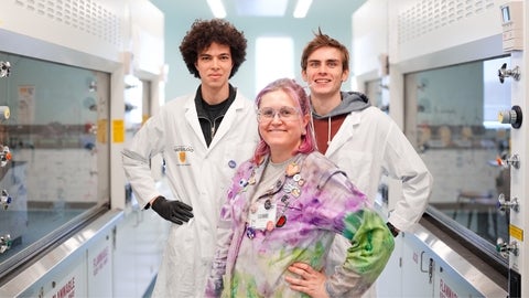 Chemistry instructor Leanne Racicot with two undergraduate chemistry students in lab coats.