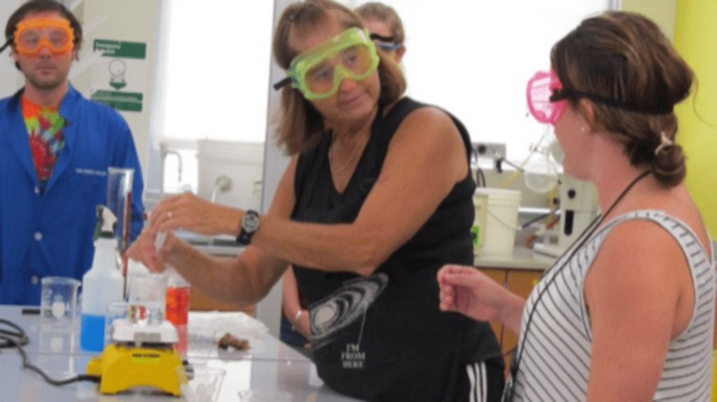 Penny Sconzo showing a demo with chemistry equipment and coloured liquids.