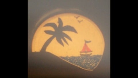 a sunset projected on a screen with a palm tree and a sailboat