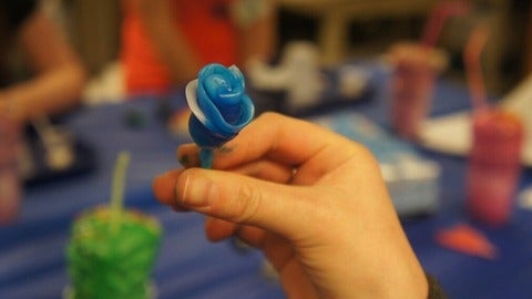 a hand holding a blue plastic flower