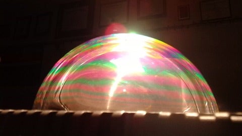 Large soap bubble with colourful refracted light on surface.
