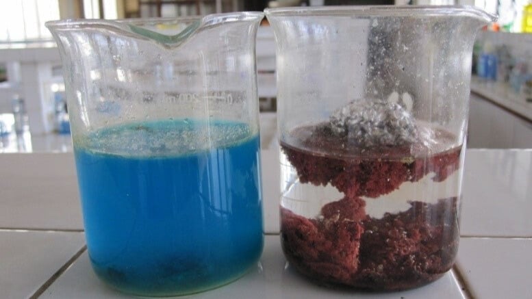 Beaker of blue solution beside beaker with red precipitate in clear solution.