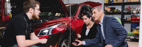 Professor with students beside a car