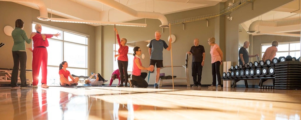 Older adults practicing yoga and exercise with trainers.