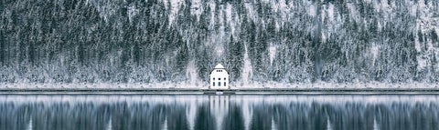 small white building on a lake surrounded by trees