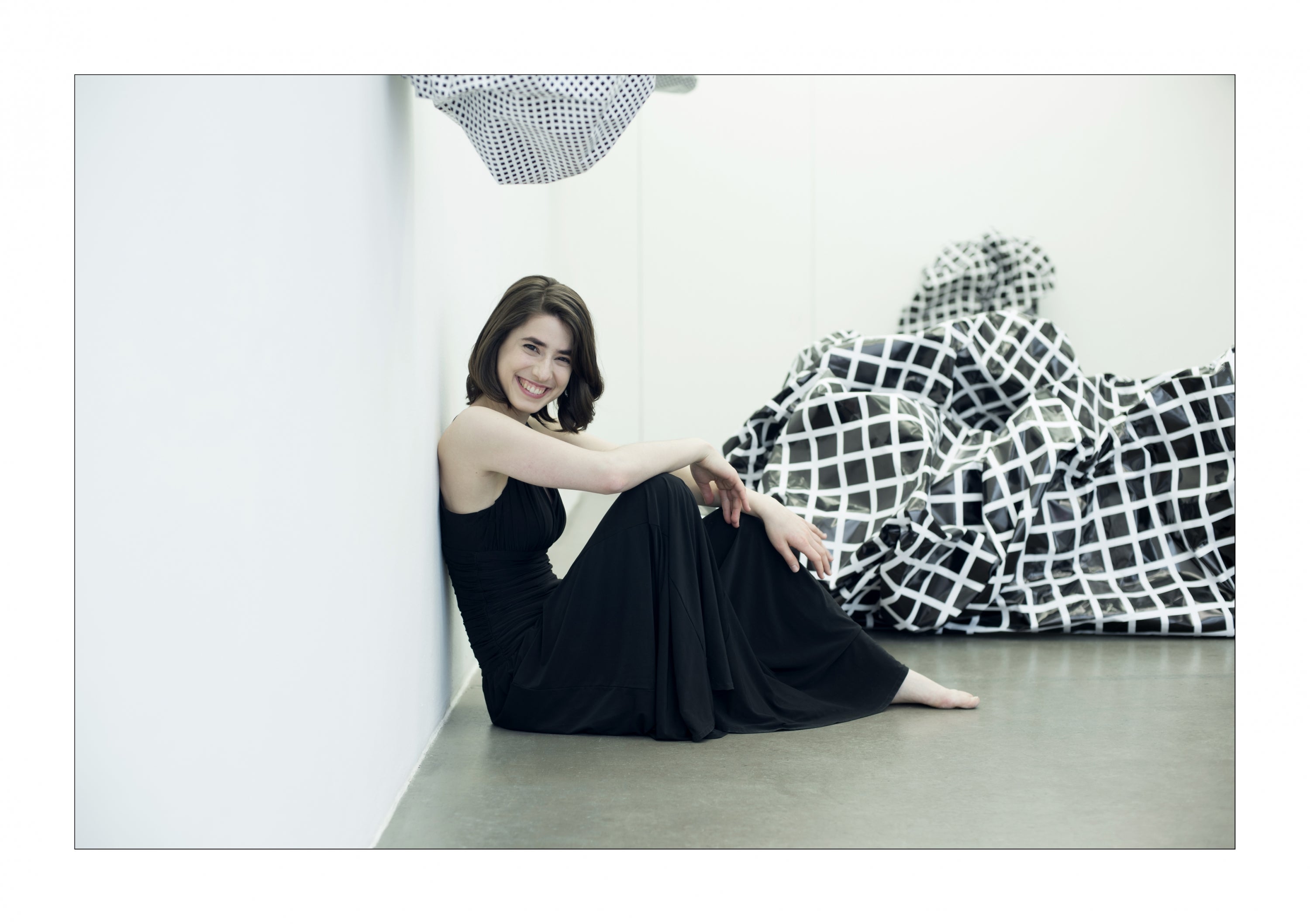 Photo of Austrian pianist Ann Magdalena Kokits in a black dress, sitting on the floor.