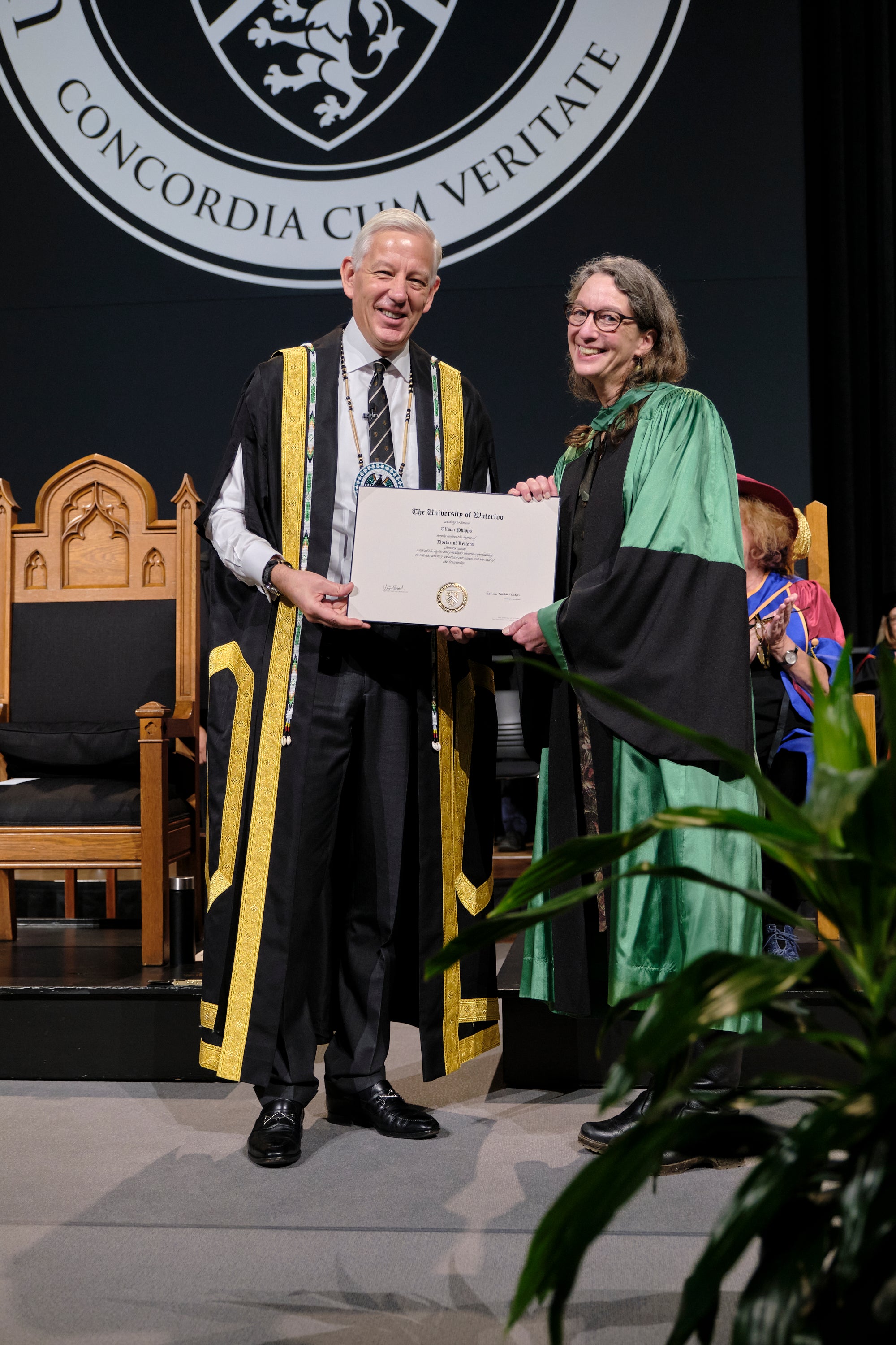 Two people standing holding an honorary doctorate.