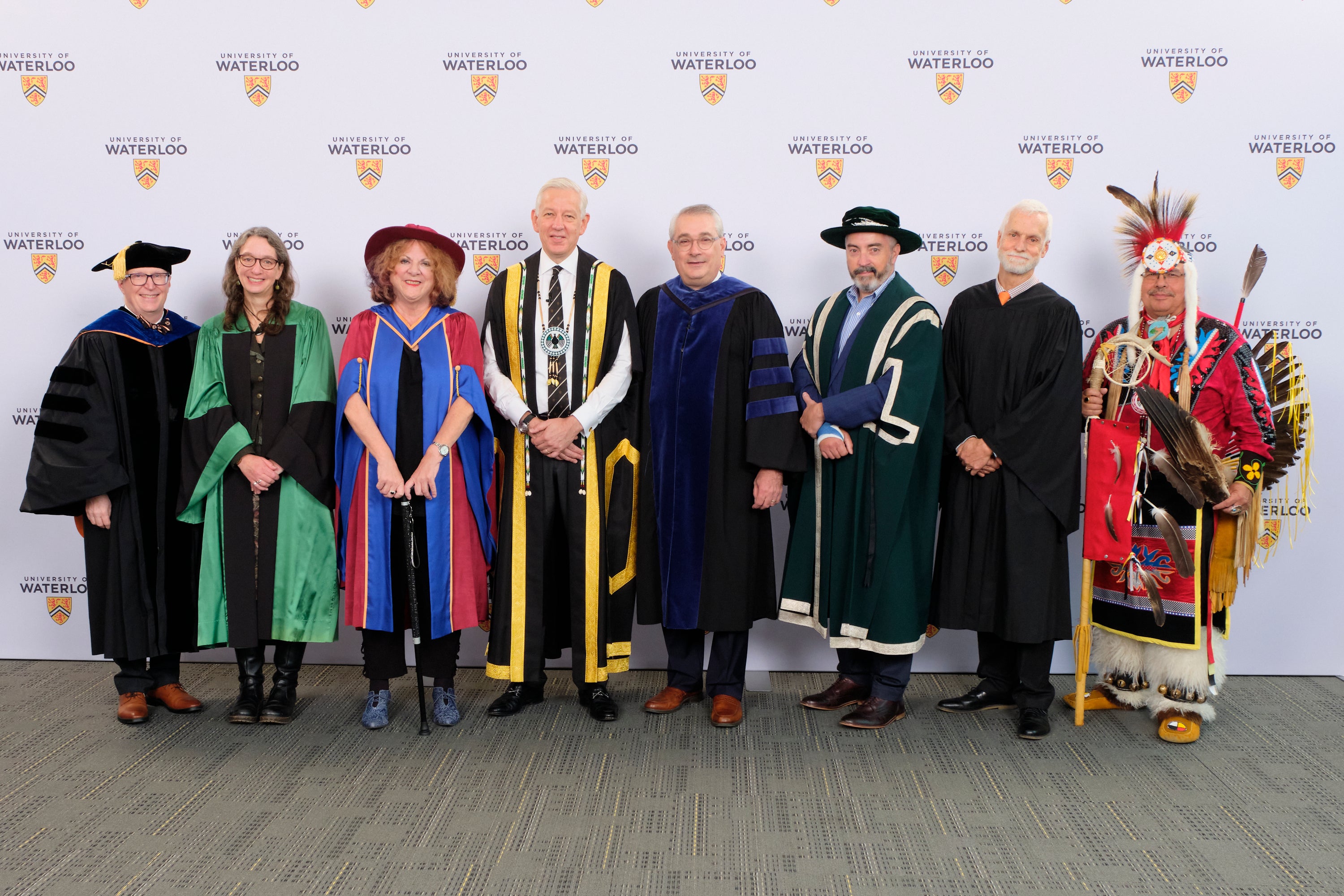 Eight people standing in a row for convocation.