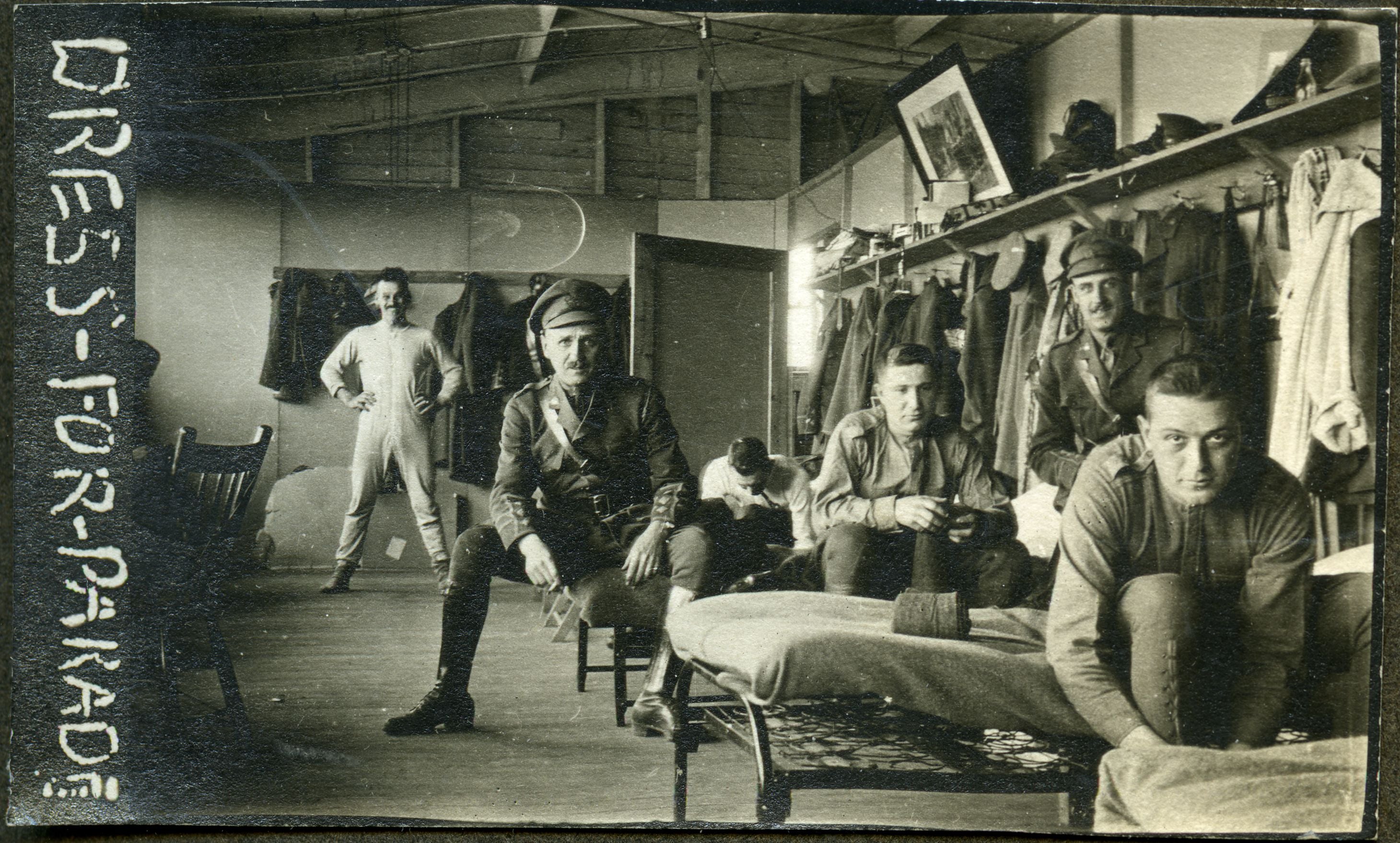 Several WWI soldiers in barracks getting dressed.