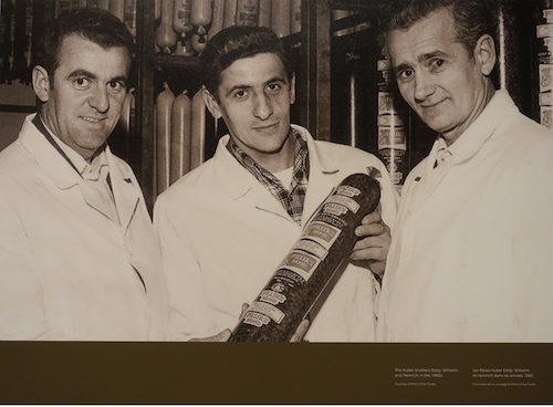 3 men hold a piller sausge - Huber Brothers