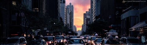 Cars wait to advance through an intersection in New York City at dusk.