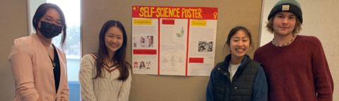Three students stand in front of a poster 