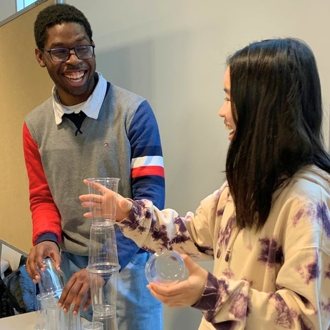 Two students stacking plastic cups and laughing